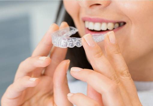 Young smiling woman holding invisalign braces