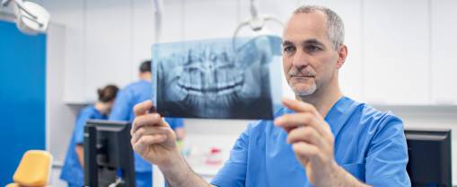 male orthodontist holding X-ray image